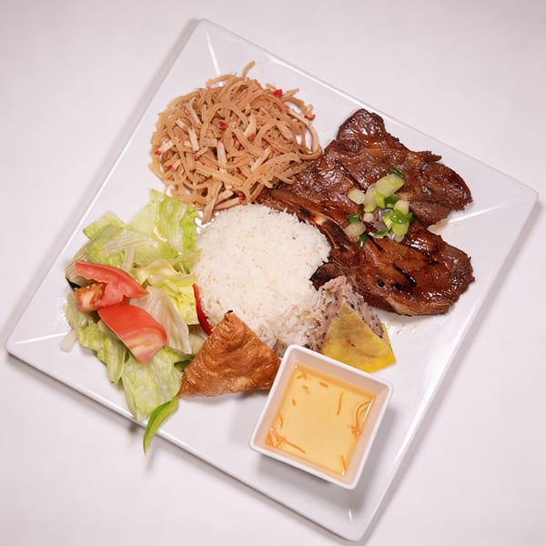 Vietnamese grilled pork chops with rice, salad, shredded pork skin, and a fried egg roll.