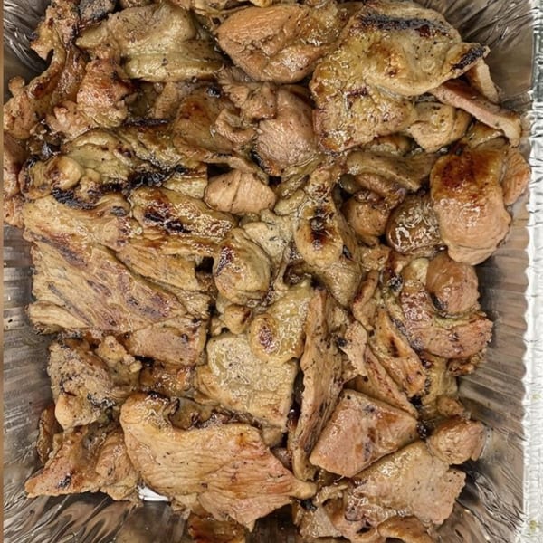 Close-up of grilled Vietnamese pork slices with char marks in a foil container.