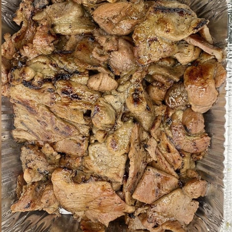 Close-up of grilled Vietnamese pork slices with char marks in a foil container.