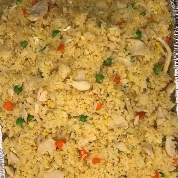 Close-up of chicken fried rice with peas and carrots in a foil pan from Saigon Pho.